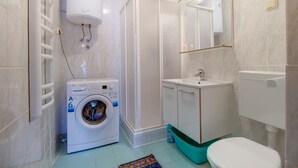 A compact bathroom with a washing machine, a sink, and a toilet. - Two-room apartment Simpatico located in the village of Artatore. (Cunski)