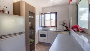A compact kitchen with a built-in oven, a sink, and a window providing natural light. - Two-room apartment Simpatico located in the village of Artatore. (Cunski)