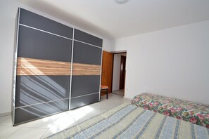 Un dormitorio con un armario grande, una cama con colcha floral y una silla.