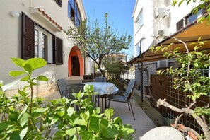 Un patio al aire libre con una mesa y sillas, rodeado de follaje y una valla.