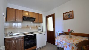 A compact kitchen with wooden cabinets, a built-in oven, and a coffee maker. - Studio Rahela 3 in Mali Lošinj, Zagazinjine. Suitable for 2 people. (Mali Losinj)