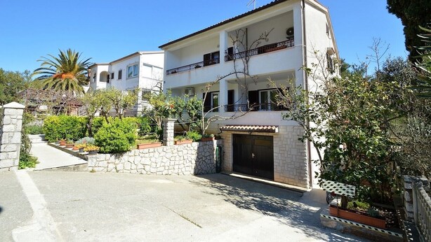 A two-story building with a balcony, a stone wall, and a gate. - Studio Rahela 3 in Mali Lošinj, Zagazinjine. Suitable for 2 people. (Mali Losinj)