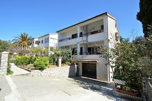 A two-story building with a balcony, a stone wall, and a gate. - Studio Rahela 3 in Mali Lošinj, Zagazinjine. Suitable for 2 people. (Mali Losinj)