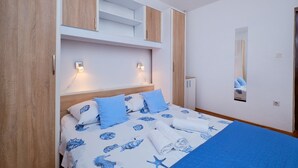 Un dormitorio con cama, ropa de cama azul, un espejo y armarios empotrados de madera.
