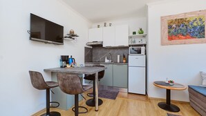 A compact kitchen with a TV, a microwave, and a small dining area with bar stools.
