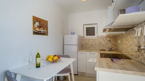 Uma cozinha compacta com uma mesa branca, geladeira, micro-ondas e pia.