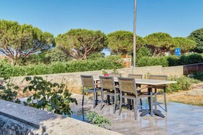 An outdoor patio with a table and chairs, surrounded by greenery and trees. - Apartment Blaz 1, in Mali Lošinj in a quiet location. (Mali Lošinj)