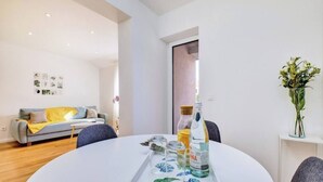 A modern living room with a round white table, grey sofa, and a vase with flowers. - Apartment Blaz 1, in Mali Lošinj in a quiet location. (Mali Lošinj)
