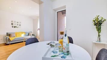 Una sala de estar moderna con una mesa redonda blanca, un sofá gris y un florero con flores.