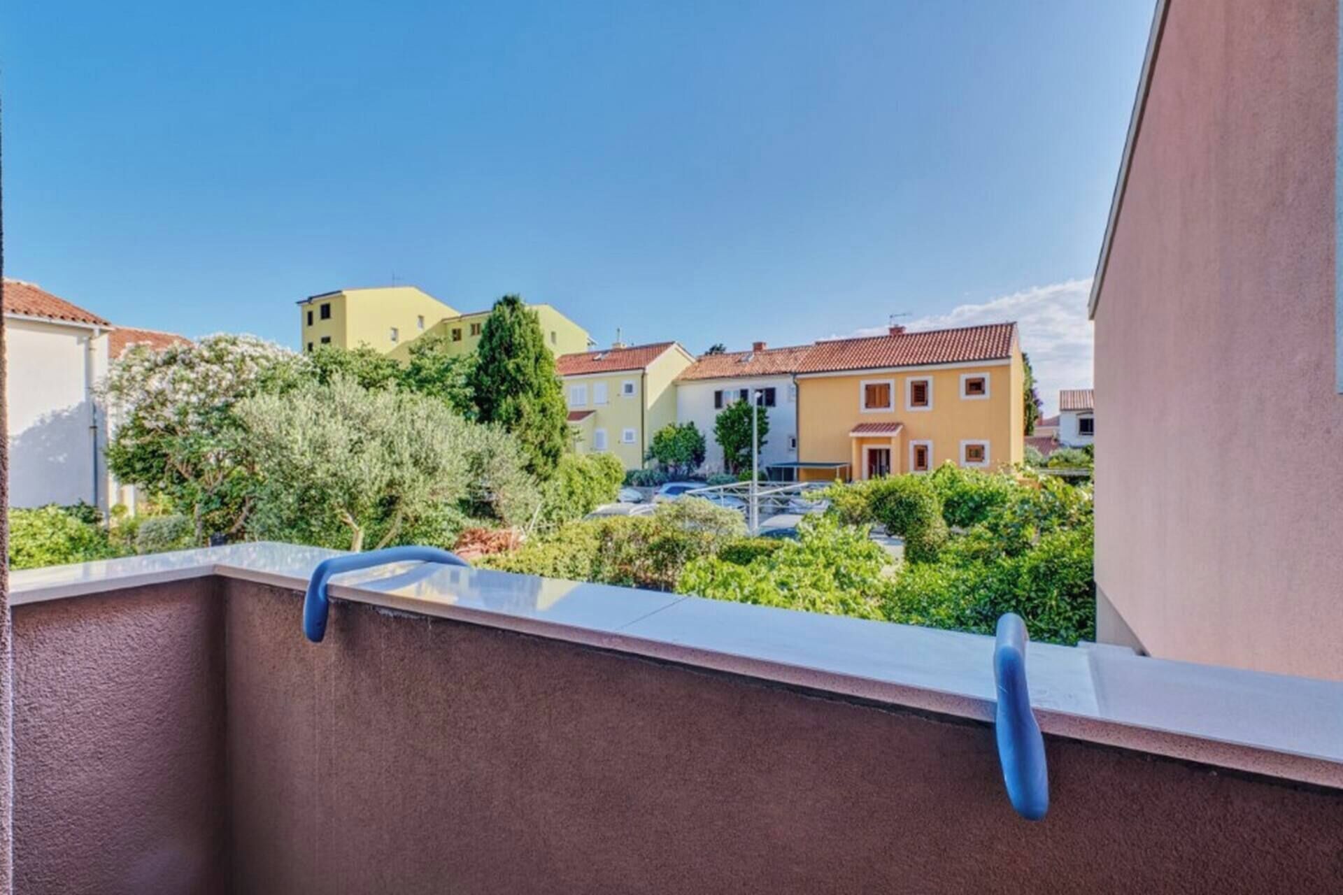 Un balcón con vistas a edificios residenciales y vegetación.