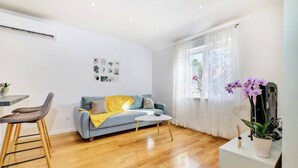 A modern living room with a sofa, coffee table, and a dining area with chairs. - Apartment Blaz 1, in Mali Lošinj in a quiet location. (Mali Lošinj)