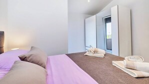 A modern hotel room with a large bed, a window, and a bathroom visible through the door. - Apartment Blaz 1, in Mali Lošinj in a quiet location. (Mali Lošinj)
