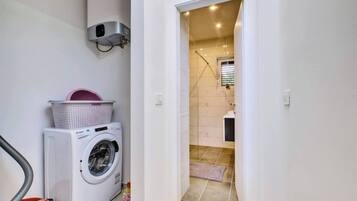 Uma área de lavanderia com máquina de lavar, secadora e aquecedor de água.