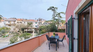 A balcony with a table and chairs, overlooking a residential area with houses and trees. - Apartment Dino 1, situated on the ground floor, ideal for four people. (Mali Lošinj)