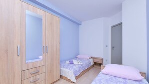 A bedroom with a large wardrobe, two single beds, and a door. - Apartment Dino 1, situated on the ground floor, ideal for four people. (Mali Lošinj)