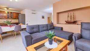 A modern living room with a grey sofa, a coffee table with a plant, and a ship model on the wall. - Apartment Dino 1, situated on the ground floor, ideal for four people. (Mali Lošinj)