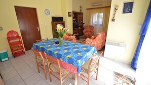 Un comedor con una mesa cubierta por un mantel azul estampado con motivos de limón, rodeado de sillas de madera.