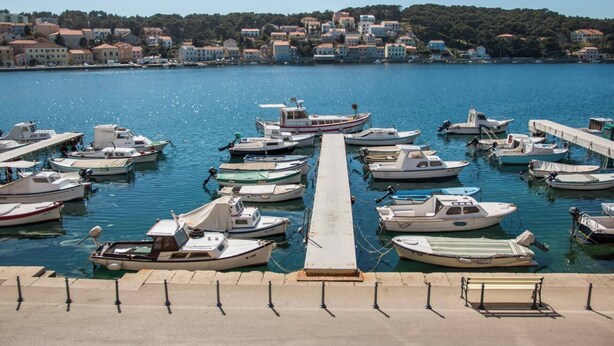 Un puerto deportivo con numerosos barcos amarrados a lo largo de un muelle, rodeado de edificios residenciales.