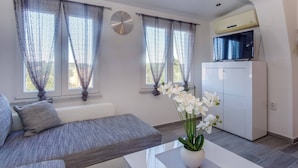 Un salon moderne avec un canapé, une table basse agrémentée de fleurs et un téléviseur posé sur un meuble.