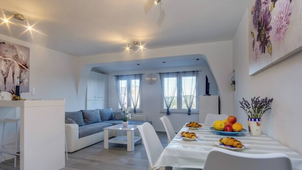 Un salon moderne comprenant un canapé, une table à manger avec des chaises et un coin cuisine.