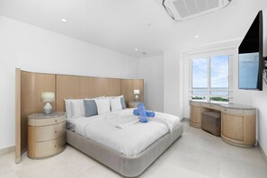 Un dormitorio moderno con una cama grande, mesitas de noche, un televisor y un ventanal con vistas.