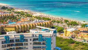 A coastal hotel with multiple floors, a pool, and a beach view. - Luxury Coastal Condo with Panoramic Views of Aruba (Noord)