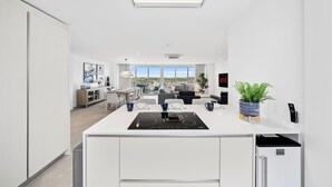 A modern kitchen with a central island, a built-in refrigerator, and a dining area with a view. - Luxury Coastal Condo with Panoramic Views of Aruba (Noord)