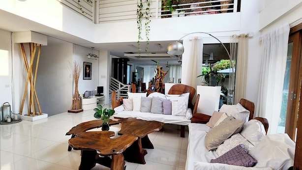 A spacious living area with a modern design, featuring a large wooden coffee table, a sofa set, and a television.