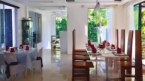 A modern dining area with a long table set for a meal, surrounded by chairs.