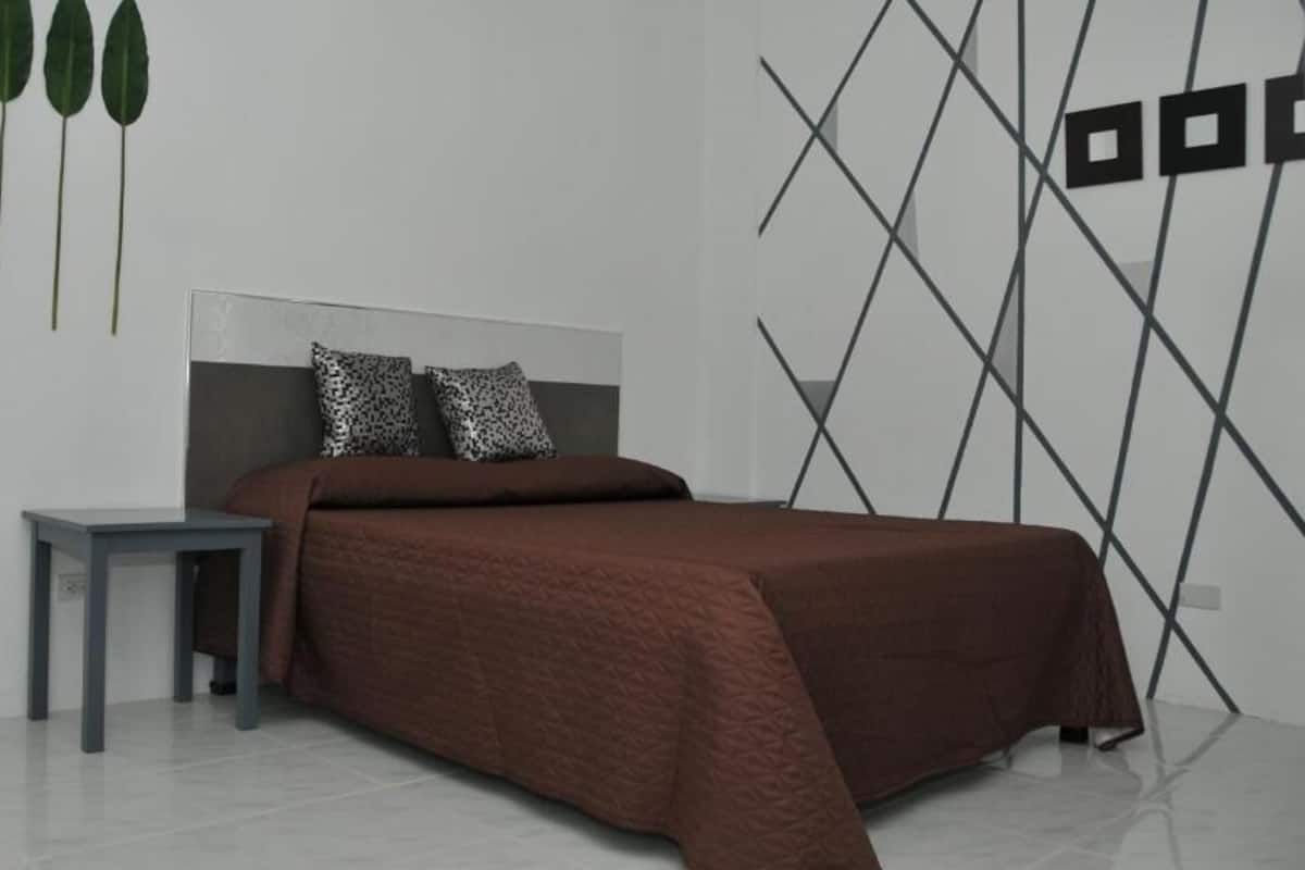 A modern bedroom with a bed, a nightstand, and a wall with geometric patterns.