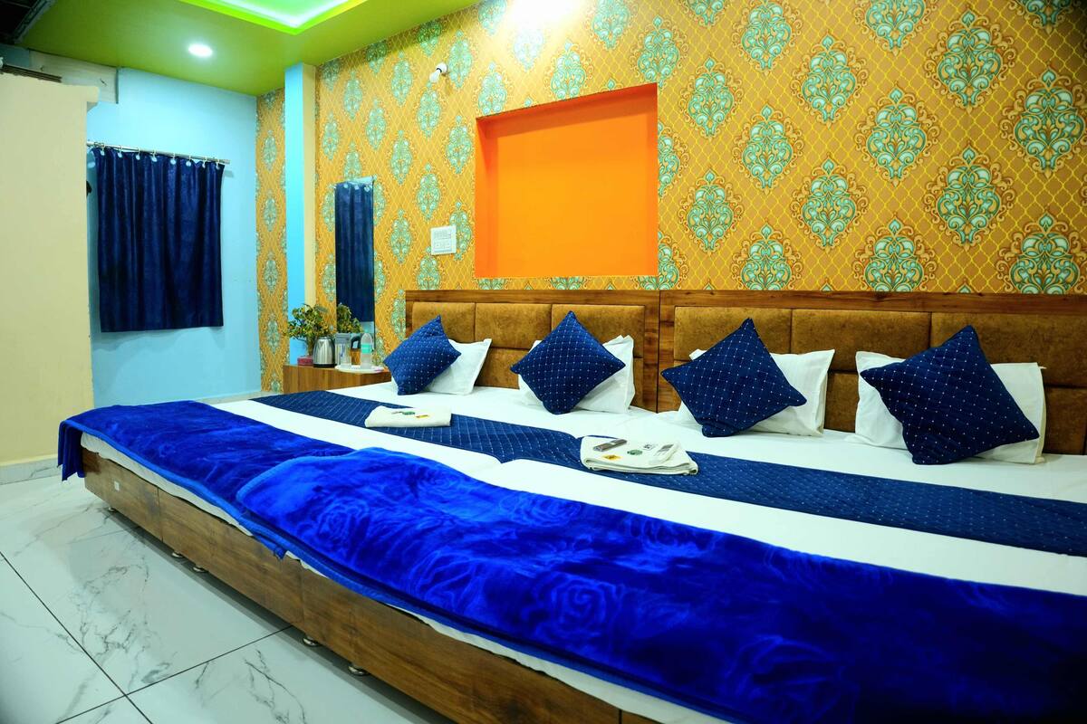 A hotel room with a large bed, a wooden headboard, and a patterned wallpaper.