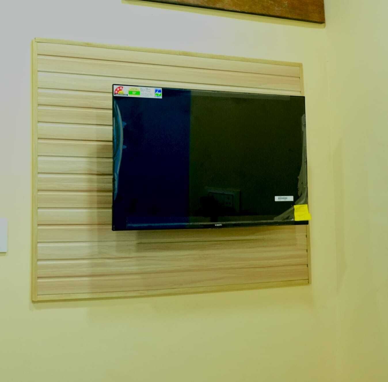 A wall-mounted flat-screen TV with a wooden panel below it.