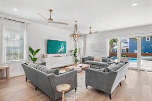 Una sala de estar moderna con sofás grises, una mesa de centro y un ventanal con persianas.