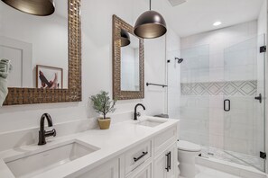 A modern bathroom with a double sink, a large mirror, and a shower area.