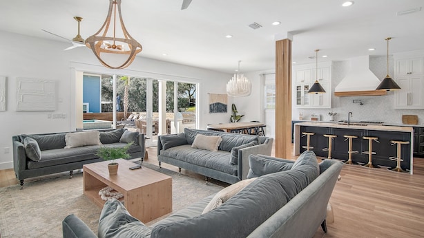 A spacious living area with a large grey sofa set, a wooden coffee table, and a ceiling fan.