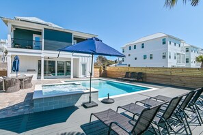 A modern house with a swimming pool, outdoor furniture, and a covered patio area.