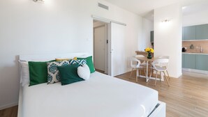 A modern bedroom with a large bed, a desk, and a kitchenette. - notaMi - Sei Milano Suite (Milan)