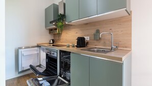 A compact kitchen with built-in appliances, a wooden backsplash, and light-colored cabinetry. - notaMi - Sei Milano Suite (Milan)