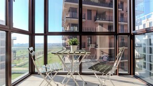 A balcony with a table and chairs, a potted plant, and a view of a residential building. - notaMi - Sei Milano Suite (Milan)