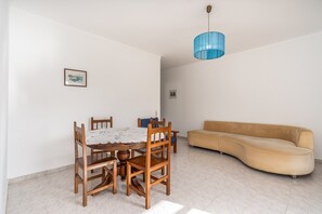 A dining area with a round table, chairs, a sofa, and a hanging light fixture. - Apartment 'Maralvor 001' with Shared Pool, Shared Garden, and Balcony (Alvor)