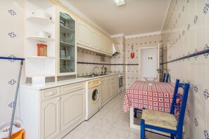 A kitchen with a washing machine, a sink, and a table with a tablecloth. - Apartment 'Maralvor 001' with Shared Pool, Shared Garden, and Balcony (Alvor)
