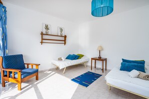 Une pièce comprenant un lit, une chaise, une petite table, une lampe et une étagère avec des plantes.