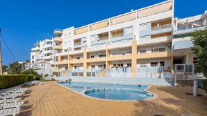 Un immeuble résidentiel à plusieurs étages doté d’une piscine, de balcons et d’une allée pavée.