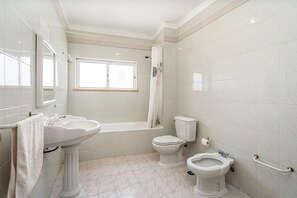 Une salle de bain comprenant un lavabo sur colonne, une baignoire, des toilettes et un bidet.