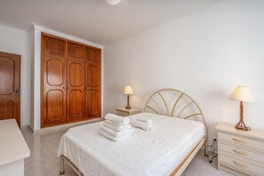 Une chambre à coucher avec un lit, des tables de chevet, une armoire et une lampe.