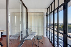 Un balcon avec un espace salon, une table et une vue sur le parking.