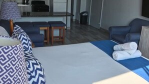 Ett hotellrum med en säng, en soffa, ett litet bord och en liten köksdel.
