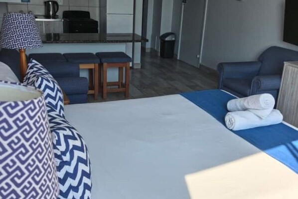 Et hotelværelse med seng, sofa, et lille bord og et tekøkken.