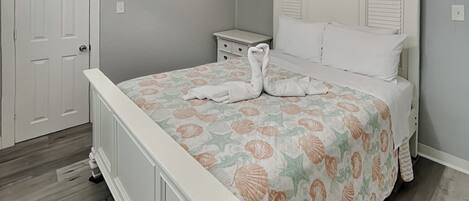 Un dormitorio con cama, mesita de noche, reloj de pared y puerta.