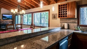 A kitchen with granite countertops, wooden cabinets, and a stone fireplace. - Palisades and North Star Ski Apres at St. Francis (Tahoe City)